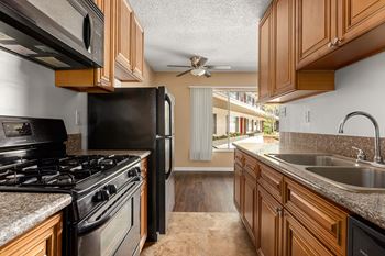 A kitchen with black appliances and wooden cabinets.